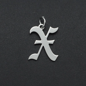 Macro view of a silver stainless steel hollow letter X pendant on a black textured surface