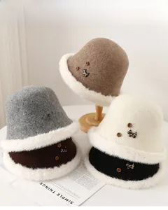 Dettaglio dei cappelli a secchiello invernali con bordo in ecopelliccia e stemma di cane