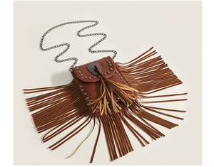 Detail of tan faux leather crossbody bag with long fringes, metal studs and skull buckle