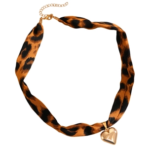 Detail eines Leopardenmuster-Chokers mit einem polierten goldenen Herzanhänger aus Metall
