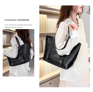 Model showcasing large black oil wax PU leather tote bag in a library setting
