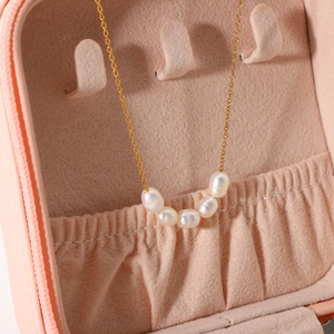Detail of five freshwater pearls on a gold-plated chain inside a pink velvet jewelry box