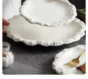 Primo piano di un elegante piatto in ceramica bianca con trama rocciosa sul bordo