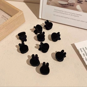Detail view of ten mini black velvet rabbit ear hair clips on a cozy desktop surface