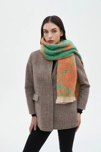 Detail shot of winter floral jacquard scarf featuring green and orange patterns and soft fringe