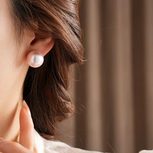 Close-up of pink round pearl stud earring on model with high-gloss finish details