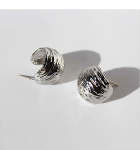 Macro detail of silver C-shaped earrings with unique brushed texture and wrinkled texture