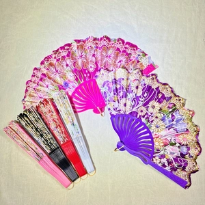 Flat lay of colorful plastic folding fans with floral patterns and golden accents