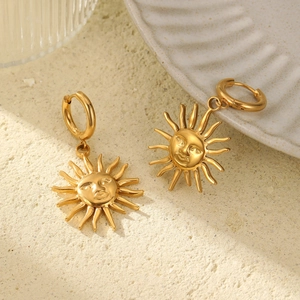 Boucles d'oreilles soleil vintage en acier inoxydable doré sur fond de sable épuré