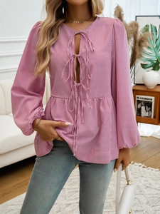 Detailed close-up of pink striped blouse featuring elegant bow tie neck and ruffle hem design