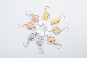 Detail view of hollow angel and girl earrings with white pearls in three metal finishes