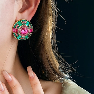 Close-up of vintage round earrings with pink and green crystals on a model