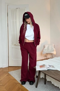 Detail view of a burgundy zip-up hoodie set with matching wide-leg sweatpants on a model