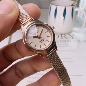 Elegant rose gold quartz watch with a round dial and mesh metal strap held by hand