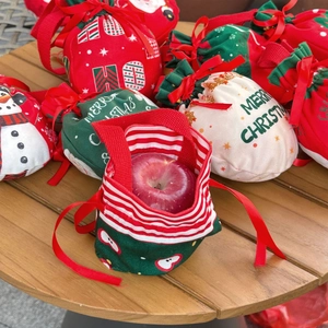 Detail of Christmas drawstring gift bags with Santa patterns on a rustic wooden table
