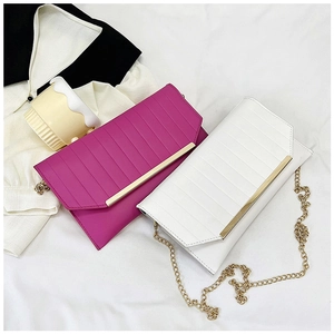 Flat lay of elegant textured envelope handbags in fuchsia and white with gold metal bar trim