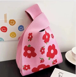 Detailed texture of pink knitted tote bag featuring red floral pattern and soft fabric