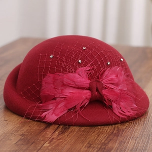 Detail of dark red wool beret with delicate diamond mesh veil and feather bow decoration