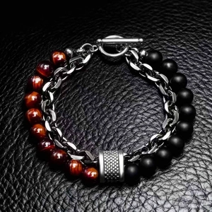 Macro shot of stainless steel chain mixed with tiger eye and black onyx beads on leather