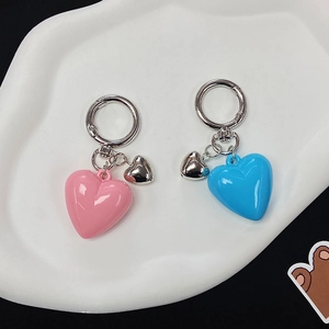 Detailed close-up of pink and blue resin heart keychains on a white cloud tray
