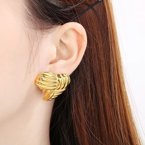 Close-up of 18K gold plated heart earrings with textured finish worn by a model