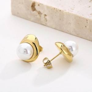 Close-up of 18K gold-plated C-shaped earrings with pearls on a textured stone