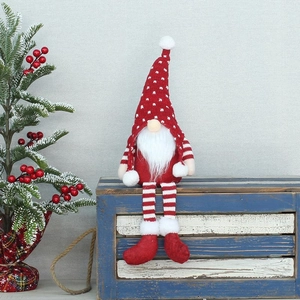 Gnomo di Natale in peluche con gambe lunghe seduto su una scatola di legno blu con albero