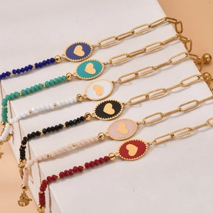 Set of 6 gold steel bracelets with colorful beads and heart charms on a beige block