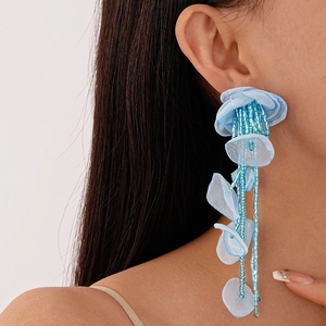 Detailed view of light blue handmade lace flower earrings with beaded tassels on model