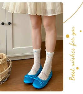 Detail of blue bow mesh socks and silk ballet flats on a warm wooden floor