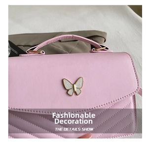 Detail shot of a pink quilted handbag featuring a white butterfly metallic buckle closure