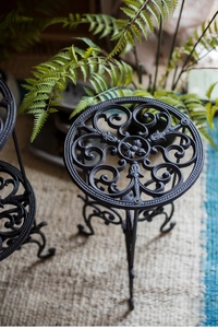 Détail d'un porte-plante en fonte vintage avec des motifs de volutes élégants