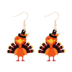 Detail of cartoon turkey earrings with black hat and maple leaf on white background