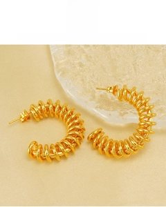 Detail of 18K gold plated spring hoop earrings on a luxury silk background texture