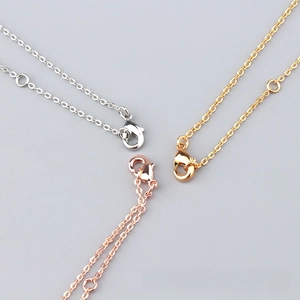 Detail of lobster clasp and extension chain on gold, silver, and rose gold bangles