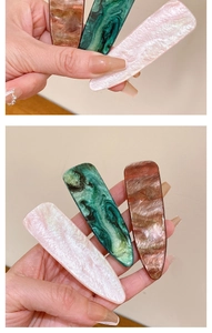 Detailed view of french vintage duckbill hair clips in pink, green, and brown acetate