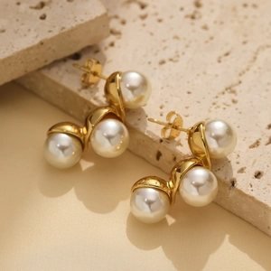 Detail of elegant gold earrings with three white pearls on a minimalist metal base