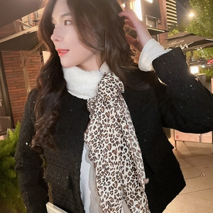 Detailed close-up of leopard print scarf with white faux fur collar on black tweed jacket