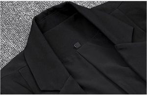Detailed view of the collar and shoulder stitching on a black blazer with fabric texture