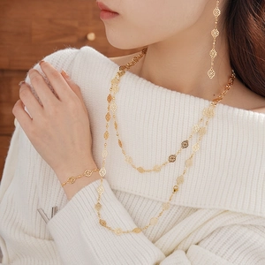 Golden hollow geometric flower jewelry set with layered necklace and earrings on a model