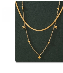 Detail of layered gold titanium necklace with herringbone chain and star pendants