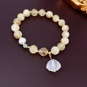Detail of beaded bracelet with natural stones, shell charm, and freshwater pearl