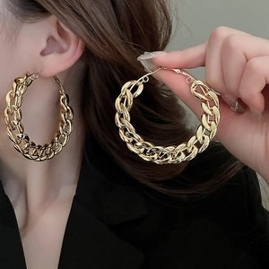 Detailed view of large gold-tone chain link hoop earrings with chunky metal texture