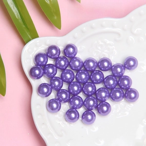 Close-up of 8mm deep purple faux pearl beads for DIY jewelry and crafts in a white plate