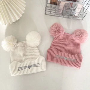 Winter knit hat for girls featuring dual pom-poms and cute embroidered cat face design