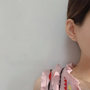 Close-up of asymmetrical gold flower stud earring with zircon details worn by a model