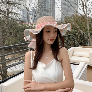 Detail of summer straw hat with wavy brim, pink chiffon bow and elegant white pearls