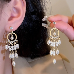 Close-up of elegant long tassel earrings with white pearls and sparkling zircons