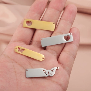 Handheld view of stainless steel hollow heart and butterfly charms in gold and silver finish