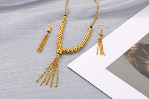 Dettaglio del set collana e orecchini dorati con nappe su seta grigia elegante